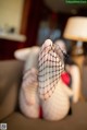 A woman in fishnet stockings is sitting on a couch.