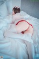 A woman in a red and white outfit laying on a bed.