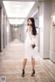 A woman in a white dress standing in a hallway.