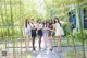 A group of young women standing next to each other in a bamboo forest.