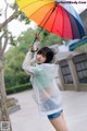 A woman holding a colorful umbrella in the rain.