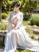 A woman in a white kimono sitting on the ground.