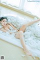 A woman laying in a bathtub covered in foam.