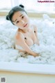 A woman sitting in a bathtub filled with foam.