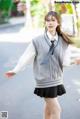 A young woman in a school uniform is walking down the street.