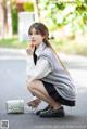 A woman sitting on the ground with a handbag and a cell phone.