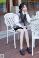 A woman sitting on a white chair with her legs crossed.