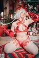 A woman in a red lingerie sitting on a rug next to a Christmas tree.