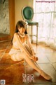 A woman sitting on the floor in a white lingerie.