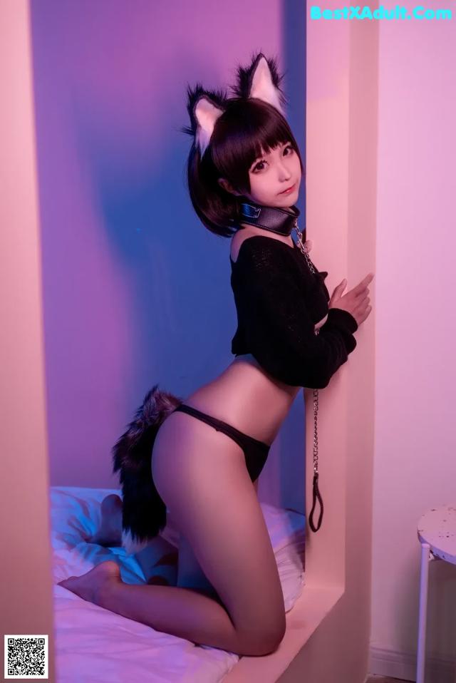 A woman in a cat costume sitting on a bed.