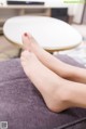 A woman's feet with red nail polish on a purple couch.