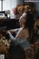 A woman sitting in front of a bunch of flowers.