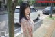 A woman standing next to a tree on a city street.