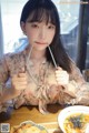 A woman sitting at a table with chopsticks in her mouth.