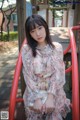 A woman sitting on a red swing in a park.