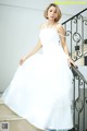 A woman in a white wedding dress standing on a staircase.