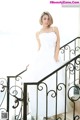 A woman in a wedding dress sitting on a staircase.