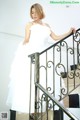 A woman in a white dress is standing on a staircase.