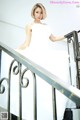 A woman in a white dress is sitting on a railing.