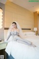 A woman in a wedding dress sitting on a bed.