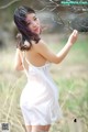 A woman in a white dress standing in a field.