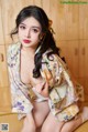 A woman in a kimono sitting on a wooden floor.