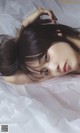 A woman laying on top of a white sheet of paper.