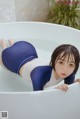 A woman in a blue and white bathing suit laying in a bathtub.