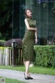 A woman in a green dress is walking down the street.