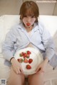 A woman sitting on a bed holding a plate of strawberries.