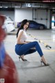 A woman sitting on the ground in a parking garage.