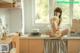 A woman sitting on top of a kitchen counter next to a sink.