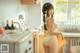 A woman in a yellow bathing suit standing in a kitchen.