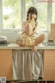 A woman sitting on top of a kitchen counter next to a window.