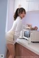 A woman in a white shirt and skirt standing in a kitchen.