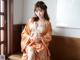 A woman in an orange kimono sitting on a window sill.