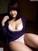 A woman in a purple cardigan and white lingerie posing for a picture.