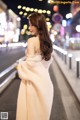 A woman in a white dress is walking down the street.