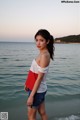 A woman standing on a beach next to the ocean.