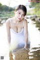 A woman in a white tank top is standing in the water.