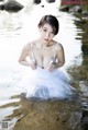 A woman in a white dress sitting in the water.