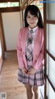 A woman in a pink jacket and plaid skirt posing for a picture.