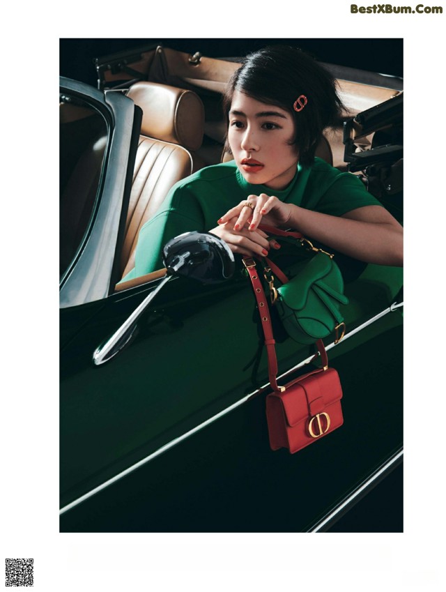 A woman sitting in the driver's seat of a green car.