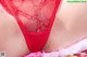 A close up of a woman wearing a red thong with a white feather.