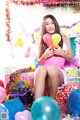 A woman sitting on top of a pile of presents holding balloons.