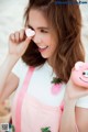 A woman holding a pink piggy bank in her hand.