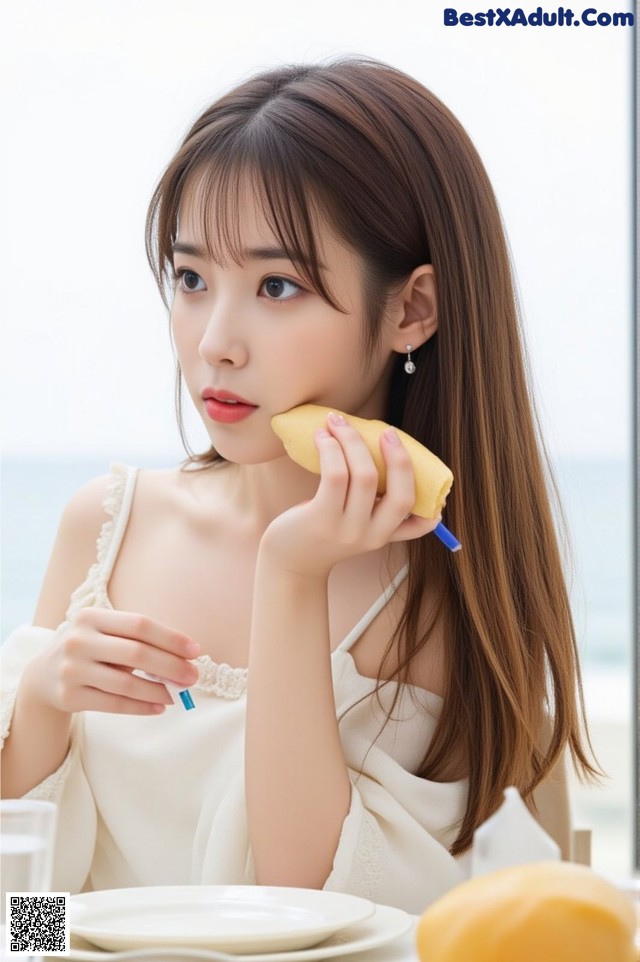 A woman sitting at a table eating a piece of fruit.