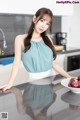 A woman standing in a kitchen next to a bowl of apples.