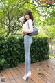 A woman standing on a wooden deck with a handbag.