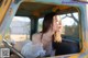 A woman sitting in the driver's seat of an old truck.